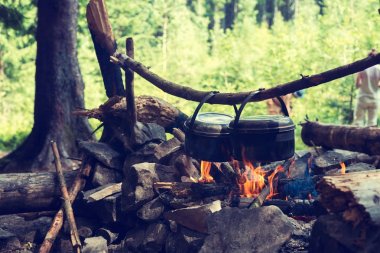 Tencere, kurum ile kaplı bir kamp ateşi üzerinde asılı olan