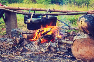 Bir kamp ateşi üzerinde asılı birkaç eski tencere
