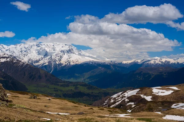 Wolken drijven boven de vallei onder de met sneeuw bedekte bergen — Stockfoto