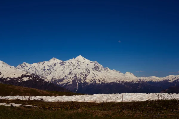 눈 덮인 산 능선 위로 창백한 달 상승 — 스톡 사진