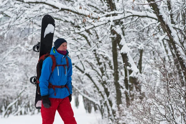 Sırt çantası ile gülümseyen snowboard ormanda yürür — Stok fotoğraf