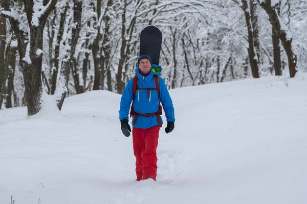 Щасливий сноубордист з рюкзаком прогулюється лісом — стокове фото