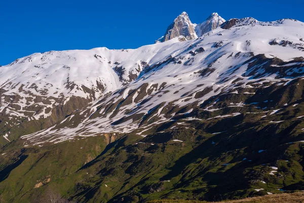 Скалистые вершины Ушбы возвышаются над заснеженными хребтами — стоковое фото