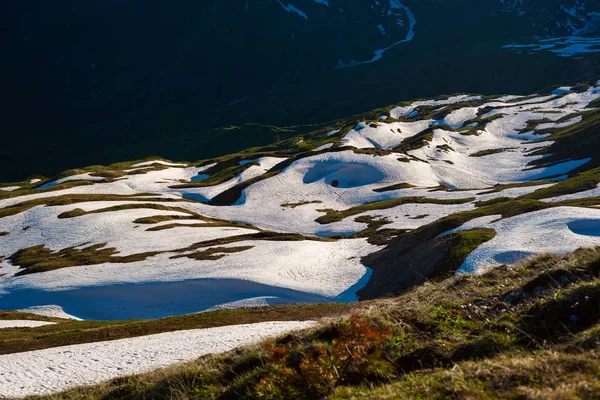 Зеленые склоны гор, покрытые остатками снега — стоковое фото