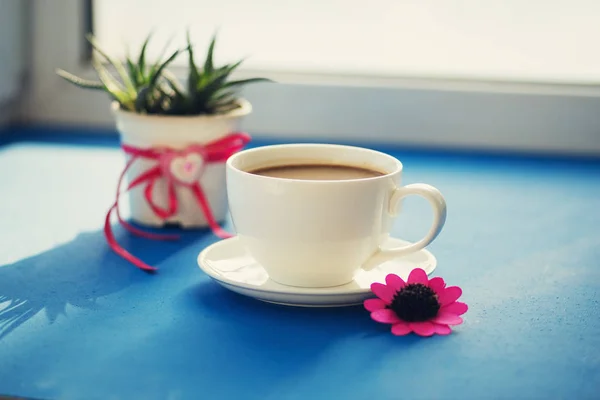 Valentine's Day - steaming cup of coffee stands on a blue surfac — Stock Photo, Image