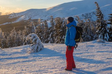 Uzun yürüyüşe çıkan kimse, sırt çantası ile dağ sırtı zamanlarda duruyor.
