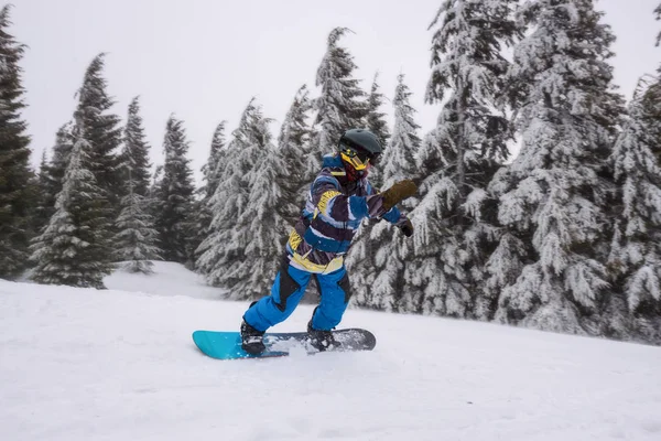 Snowboarder paseos cuesta abajo, gira a lo largo de la pendiente de la montaña — Foto de Stock