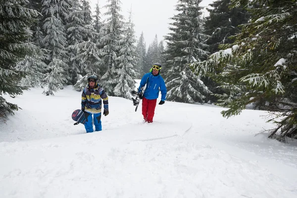 Dwóch przyjaciół snowboardzistów wznoszą się na zboczu góry — Zdjęcie stockowe