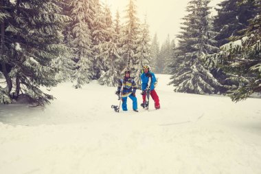 Neşeli snowboard büyük karla kaplı çam ağaçları arasında sakin ol. 