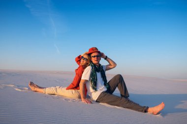 Neşeli çift oturma, sırt sırta, bir blu karşı çölde