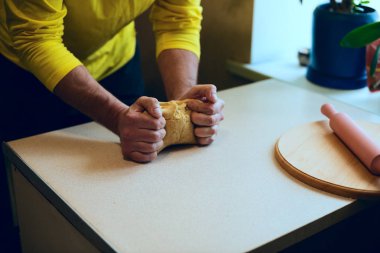 Güçlü erkek ellerin beyaz masanın üzerine hamur yoğurmak
