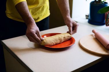 Erkekler el hamur bir parça kırmızı bir tabağa koy.