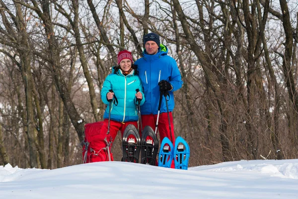 Feliz pareja de excursionistas se encuentra en un bosque de invierno al lado de snowsho — Foto de Stock