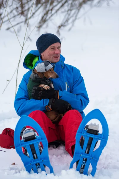 Счастливый путешественник в снегоступах обнимает смешную маленькую собаку — стоковое фото