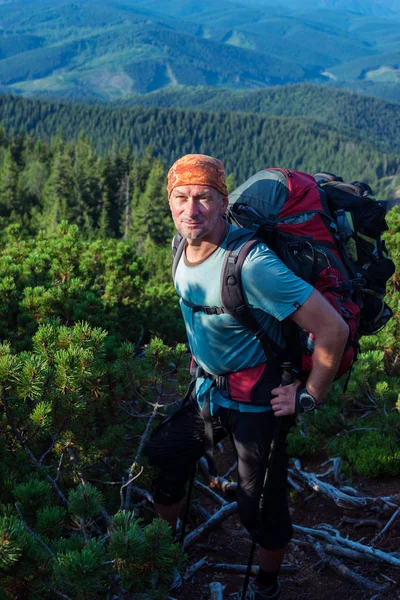 Wandelaar met grote rugzak staat op een hoogteweg — Stockfoto