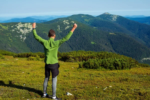 Blije wandelaar, jonge kerel staat met open armen in de bergen — Stockfoto