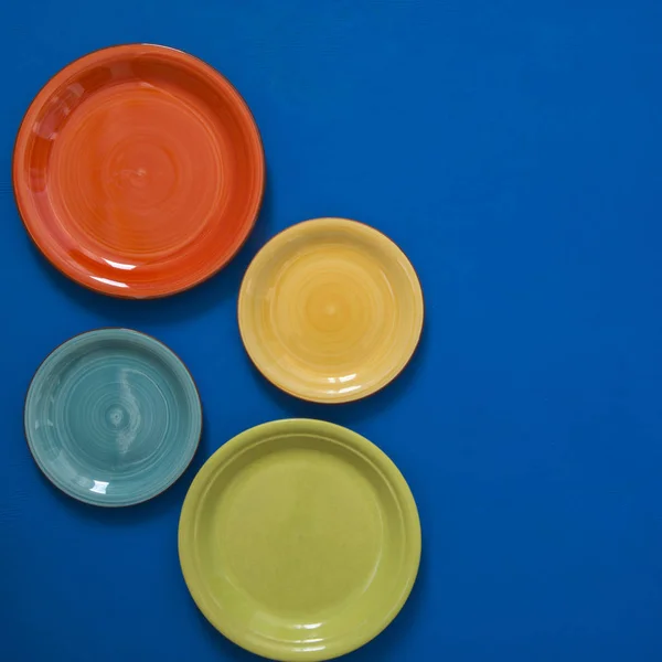 Bodegón - cuatro platos de colores en el borde de un fondo azul — Foto de Stock