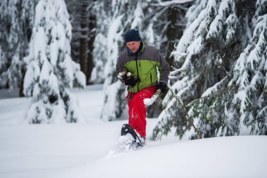 Maceracı onun elinde odun ile kar ayakkabıları içinde yürüyor