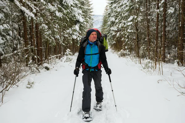 Vrolijke avonturier, met grote rugzak, is wandelen in sneeuwschoenen — Stockfoto