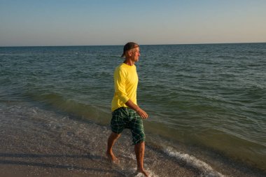 Neşeli maceraperest günbatımı sırasında sörf hat boyunca yürüyor