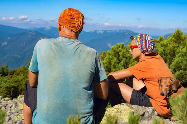 Padre y su hijo adolescente con perro divertido en las montañas — Foto de Stock