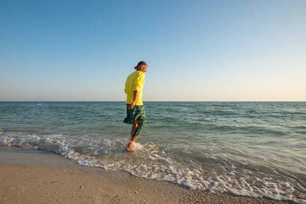 Szczęśliwy, podróżnik jest chodzenie wzdłuż linii surf i uśmiechając się — Zdjęcie stockowe