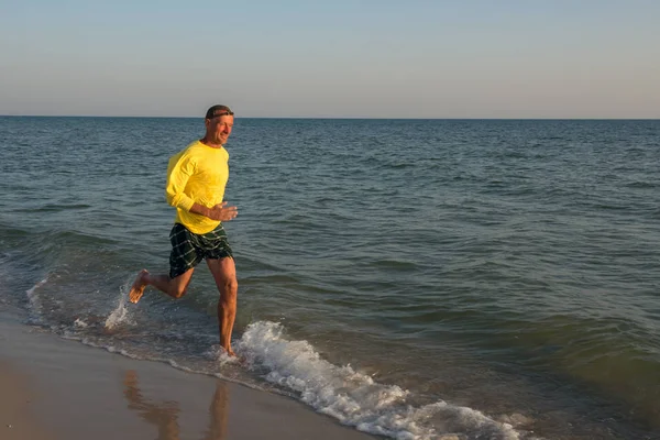 Feliz aventurero está corriendo a lo largo de la línea de surf y divertirse — Foto de Stock