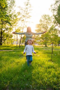 Genç anne ve küçük kızı, Kollarını açarak gülüyor