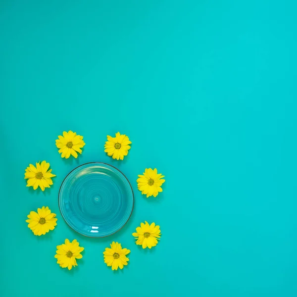 Summer background - a turquoise plate surrounded by yellow chrys