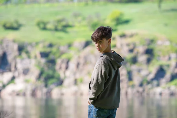 Привабливий хлопчик стоїть на березі великої річки — стокове фото