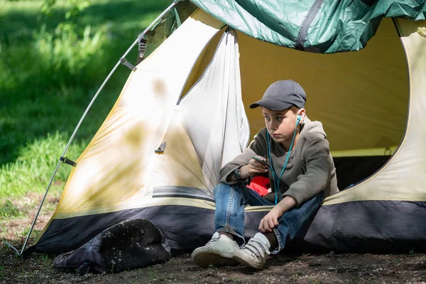 Genç çocuk bir çadır bir yeşil çayır üzerinde oturur. 