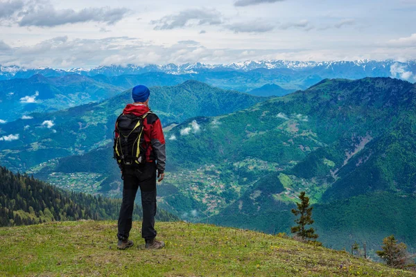 Aventureiro com mochila fica no prado verde da montanha — Fotografia de Stock