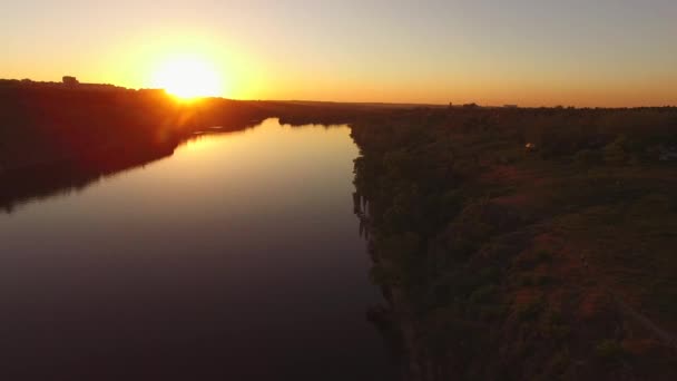Vol au-dessus de la côte rocheuse d'une grande rivière à côté d'une ville au coucher du soleil. Île de Khortitsa, rivière Dniepr, Ukraine. Feu arrière .