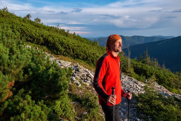 Caminhante feliz fica em uma trilha de montanha — Fotografia de Stock