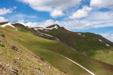 Yeşil dağ yamaçlarında kar kalıntıları ile