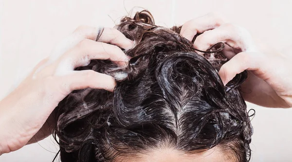 Junge Frau wäscht Haare mit Shampoo in der Dusche — Stockfoto