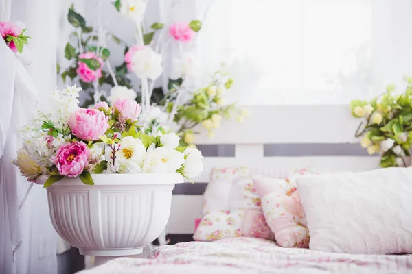 Pink and white flowers in a vase near the bed — Stock Photo, Image