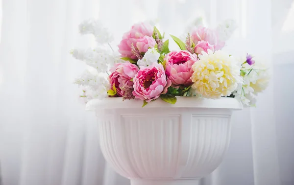 Rózsaszín és fehér virágok vázában, közel az ágy — Stock Fotó