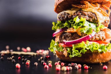 Siyah arka planda baharatlı lezzetli bir burger.