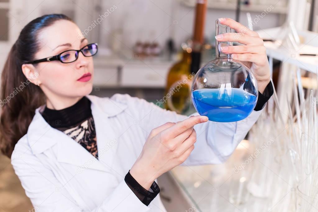 A scientist in a laboratory studying the liquid in the beaker