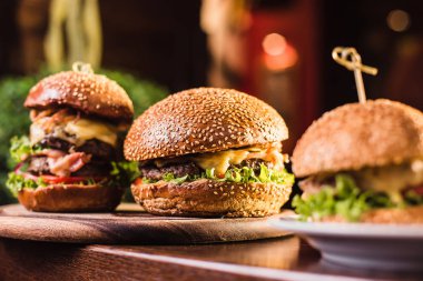 Karanlık bir arka plan üzerinde beyaz tabakta üç sulu lezzetli burger