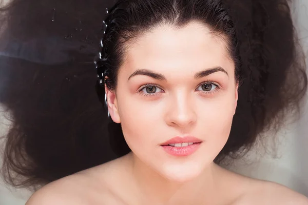 Молодая женщина в ванной комнате, чтобы смыть волосы под водой — стоковое фото
