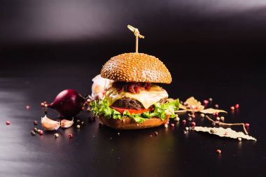 Siyah arka planda baharatlı lezzetli bir burger.