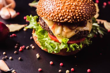 Siyah arka planda baharatlı lezzetli bir burger.