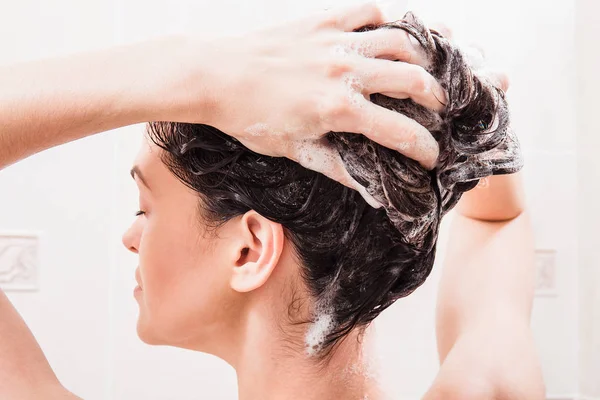 Jeune femme lavant les cheveux avec shampooing sous la douche — Photo