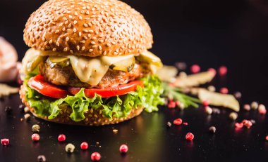Siyah arka planda baharatlı lezzetli bir burger.
