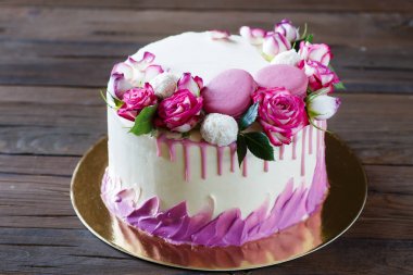 Ahşap arka plan üzerinde gül dekorasyonu ile beyaz pasta