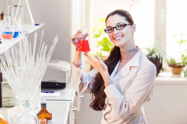 Жінка-вчена в лабораторії з позуванням на склянку — стокове фото
