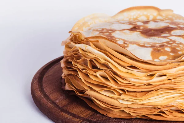 Panqueques delgados sobre un soporte redondo de madera sobre un fondo blanco — Foto de Stock