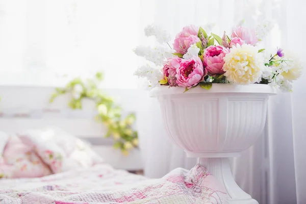 Rózsaszín és fehér virágok vázában, közel az ágy — Stock Fotó